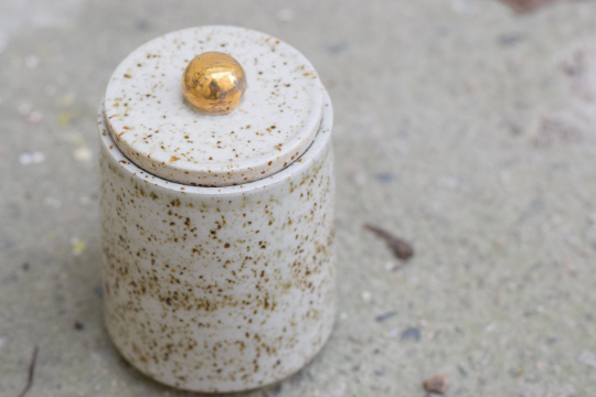 Speckled jar with gold handle.